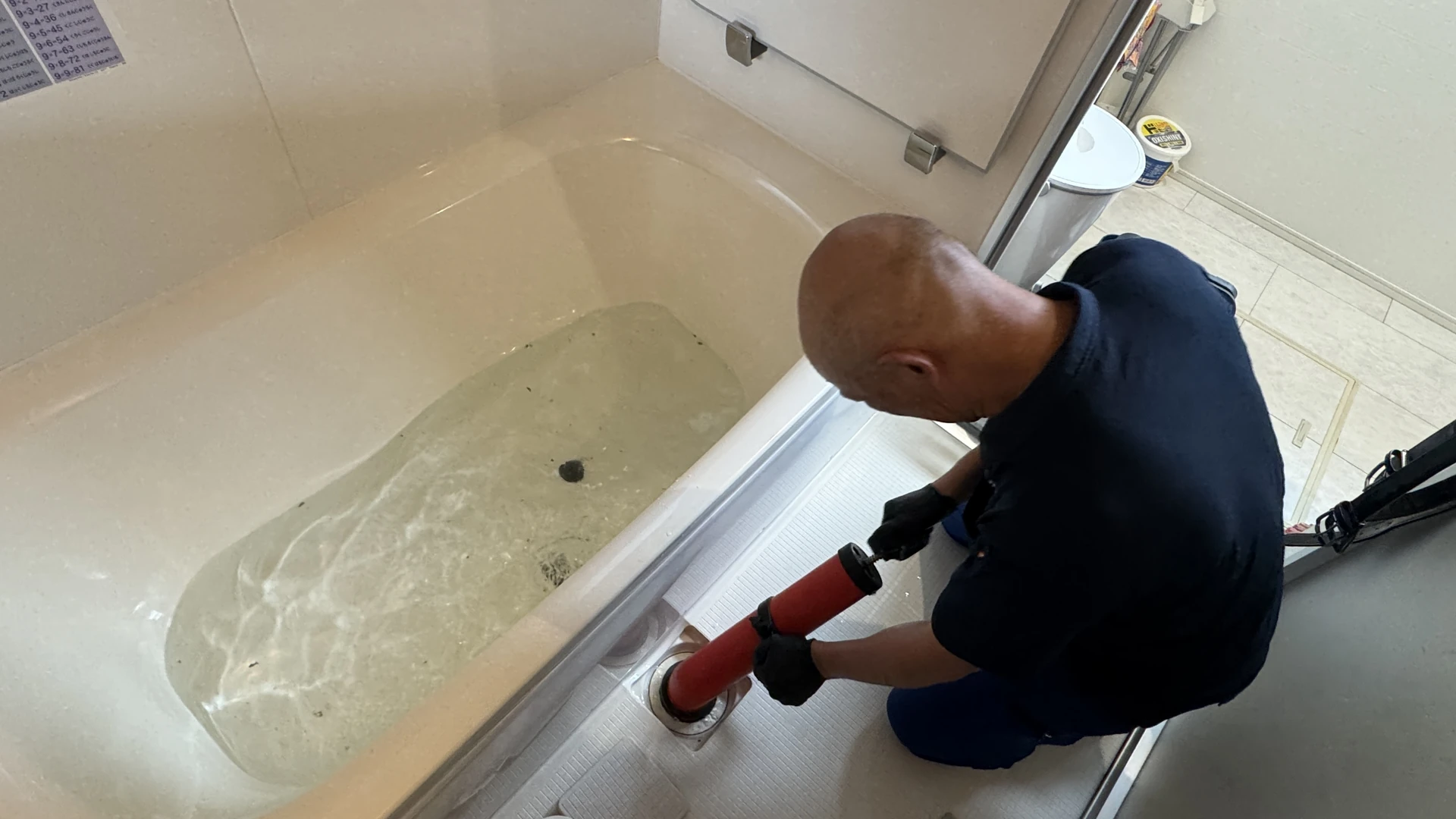 浴室の排水口で作業する手元