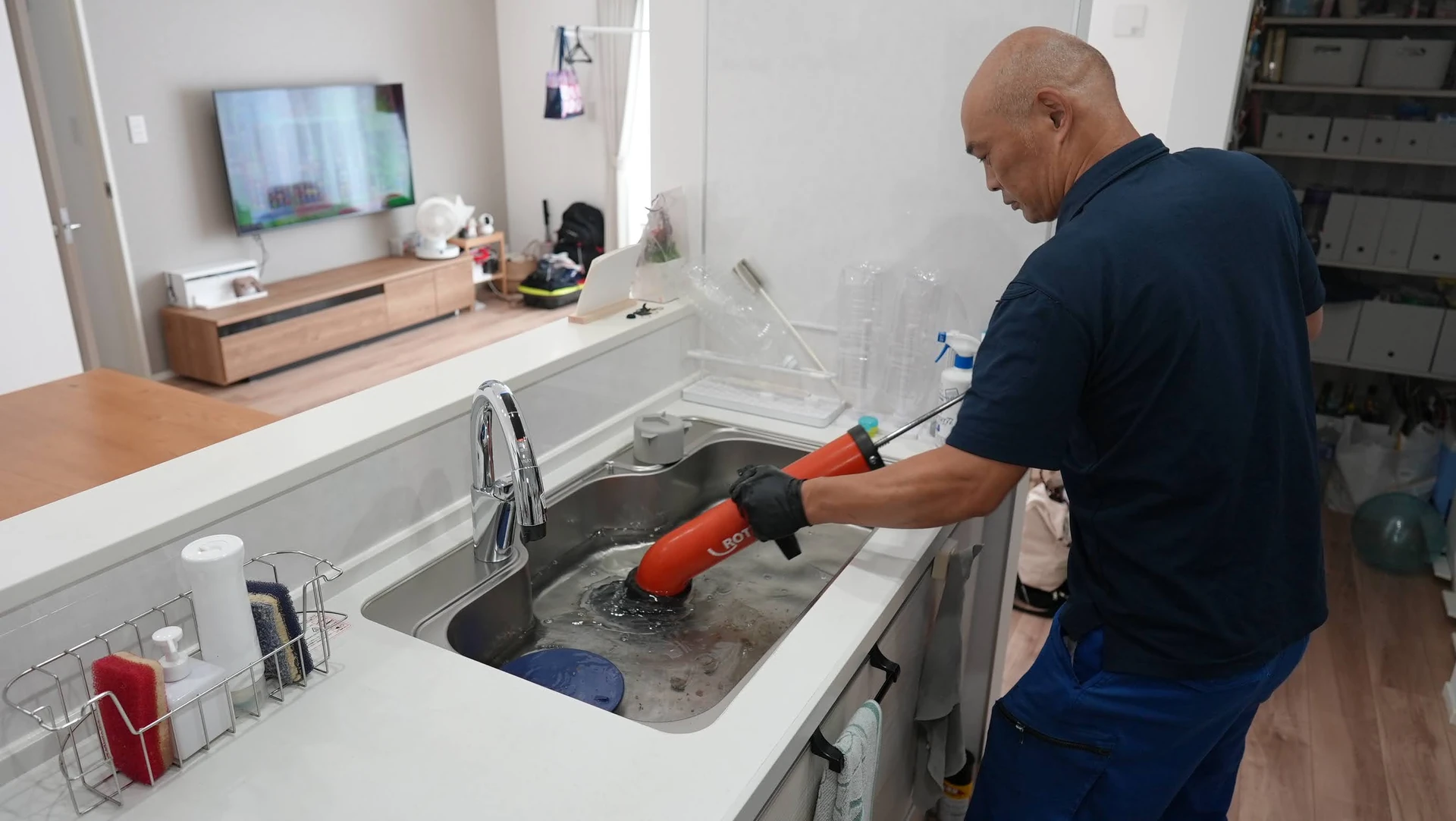 台所の排水口で作業する場面