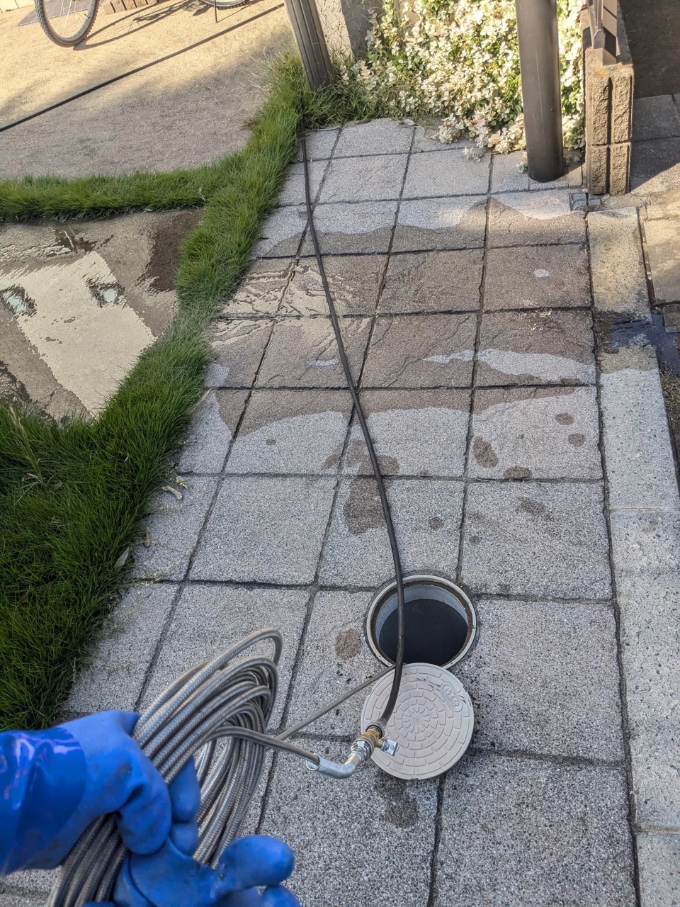 青い手袋でホースを持ち排水マスに送り込む手元