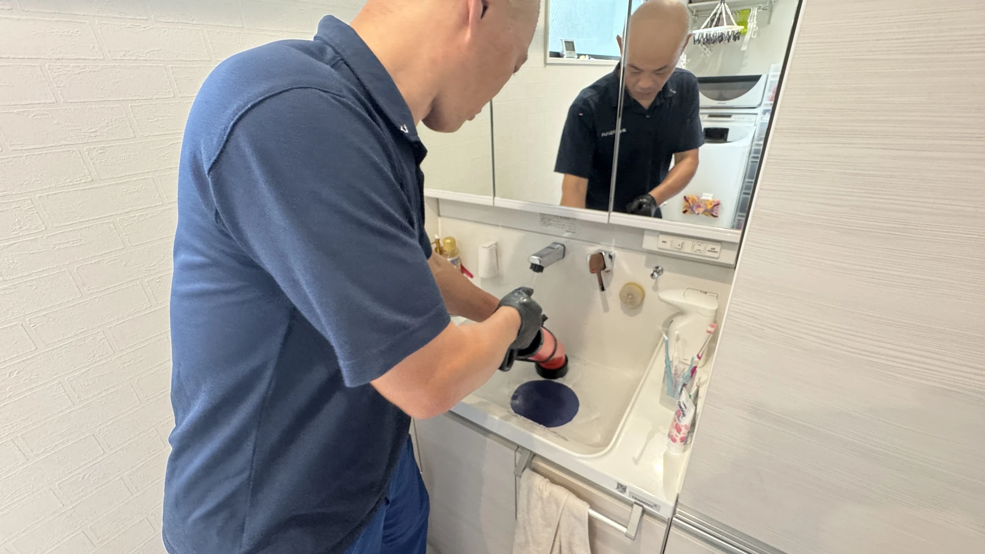 洗面台の排水口で作業する場面